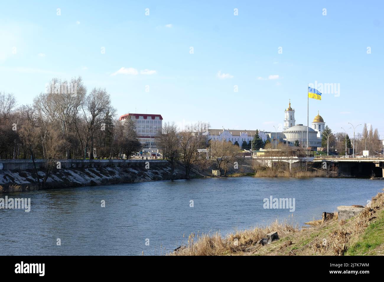 Sumy, Ukraine - April 05, 2022: Beautiful cityscape with river and flad of Ukraine. Stock Photo