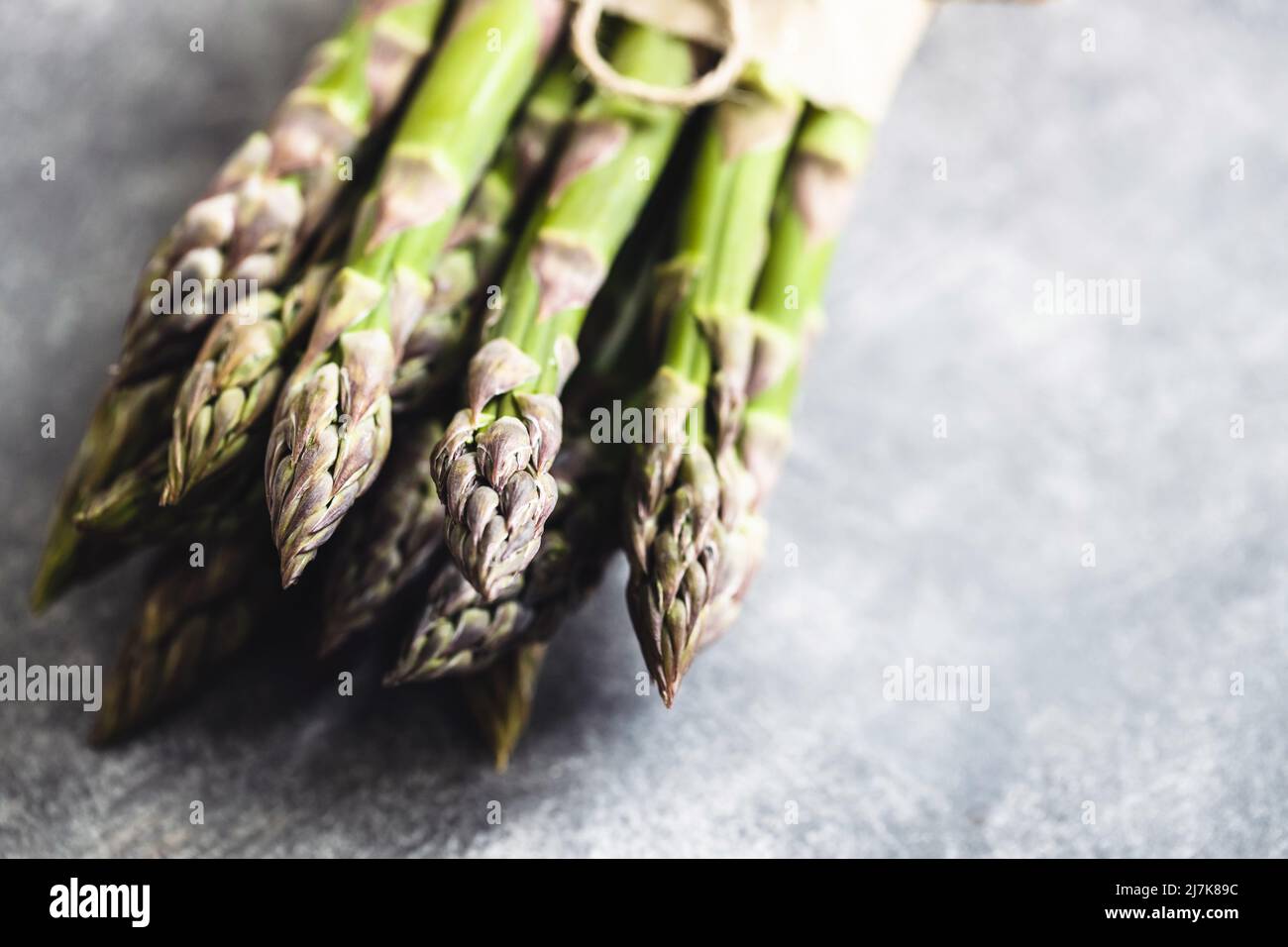 Bunch of fresh asparagus tied rope on gray table. Stock Photo