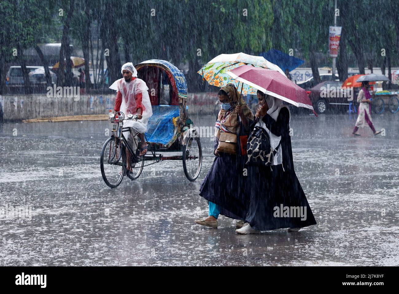 Two women cross a road with umbrellas as it rains in Dhaka, Bangladesh, May 10, 2022. REUTERS/Mohammad Ponir Hossain Stock Photo