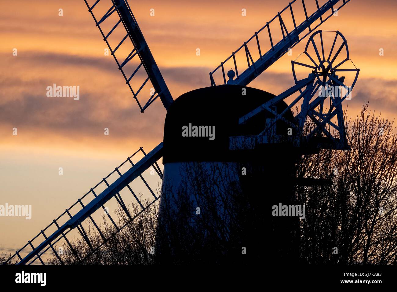 Silhouette of windmill against golden skies at sundown Stock Photo