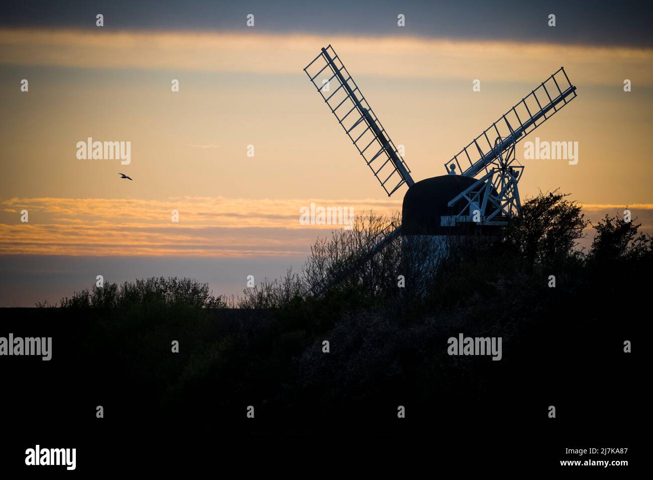 Silhouette of windmill captured at sunset in rural setting Stock Photo