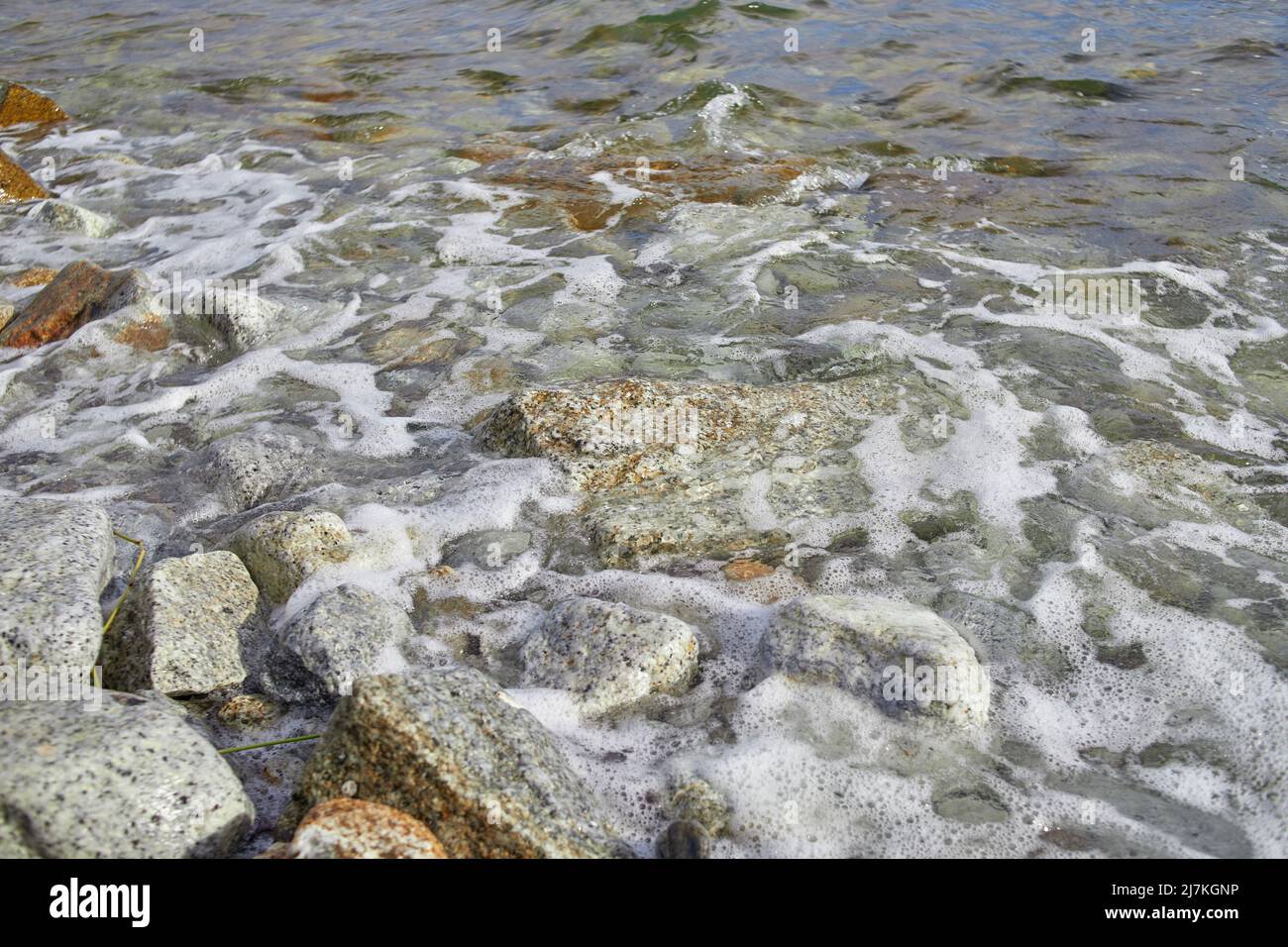 Wave splashing on the rocky beach with foam Stock Photo - Alamy