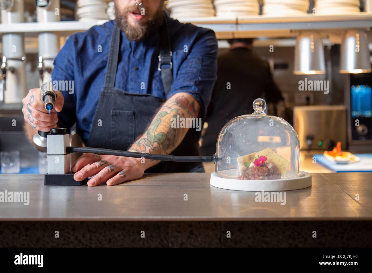 Crop anonymous male chef in uniform using smoking gun to infusing glass ...