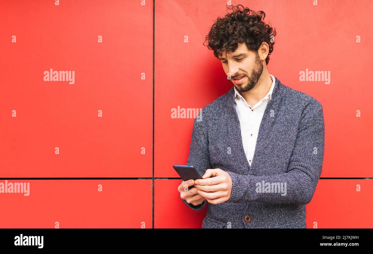Focused bearded male entrepreneur in formal wear and curly hair texting ...