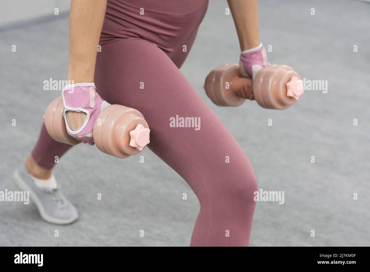 No face visible. Athletic young woman doing heavy lifting using dumbbell at the gym. Young woman exercise using dumbbell to lose weight or burn calories. Stock Photo