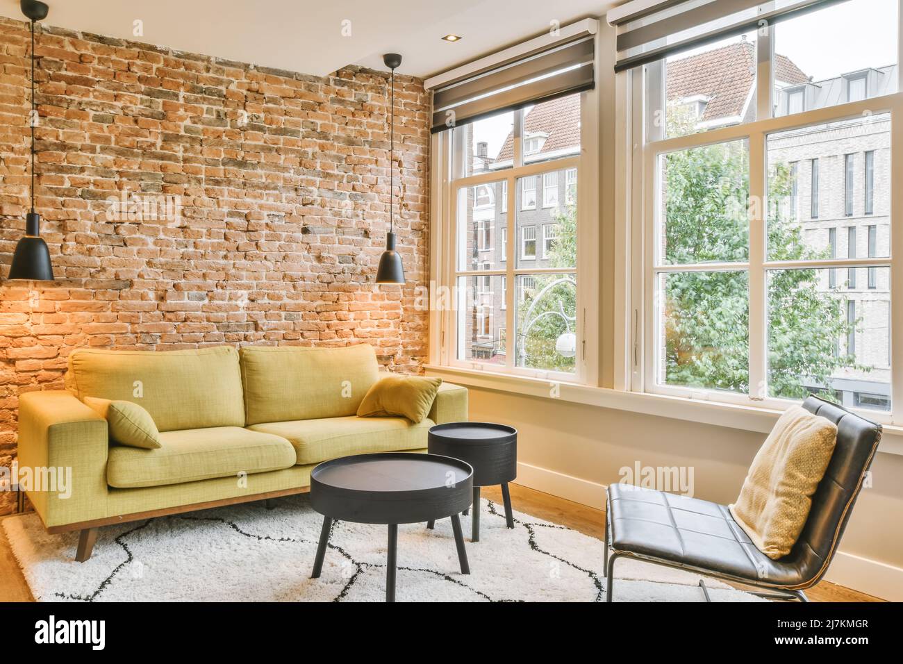 View of Comfortable sofa placed on rug near brick wall with lamps and black ...