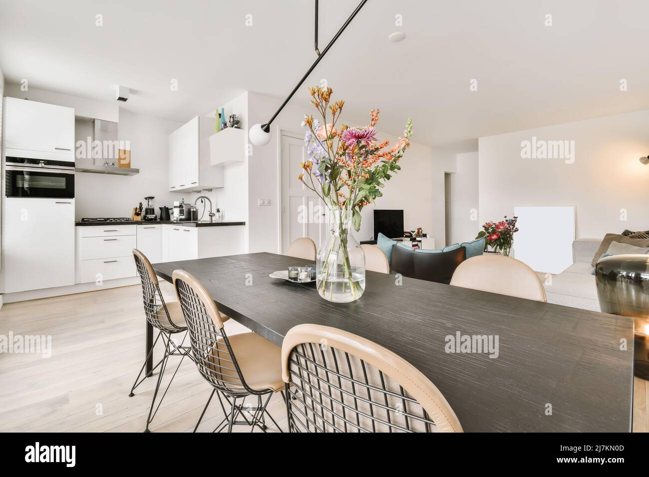 Open plan kitchen with white cabinets and utensils placed in light ...