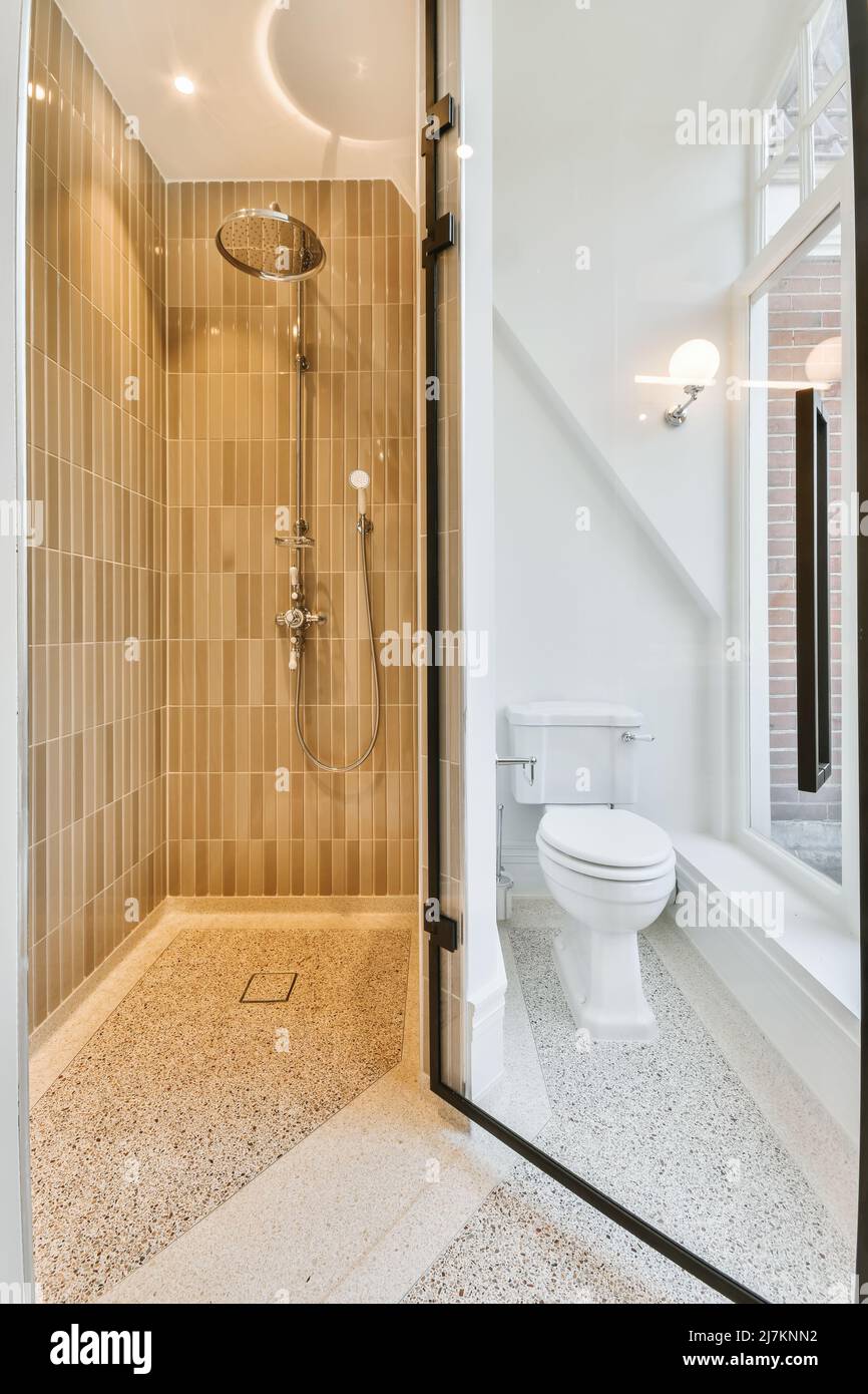 White toilet bowl near shower cabin in contemporary bathroom with beige