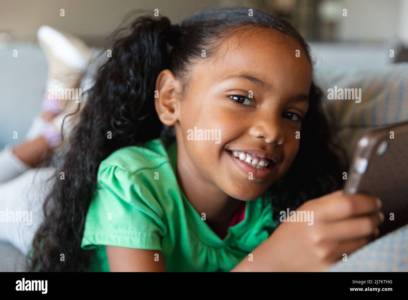 Portrait of smiling african american elementary girl using digital ...