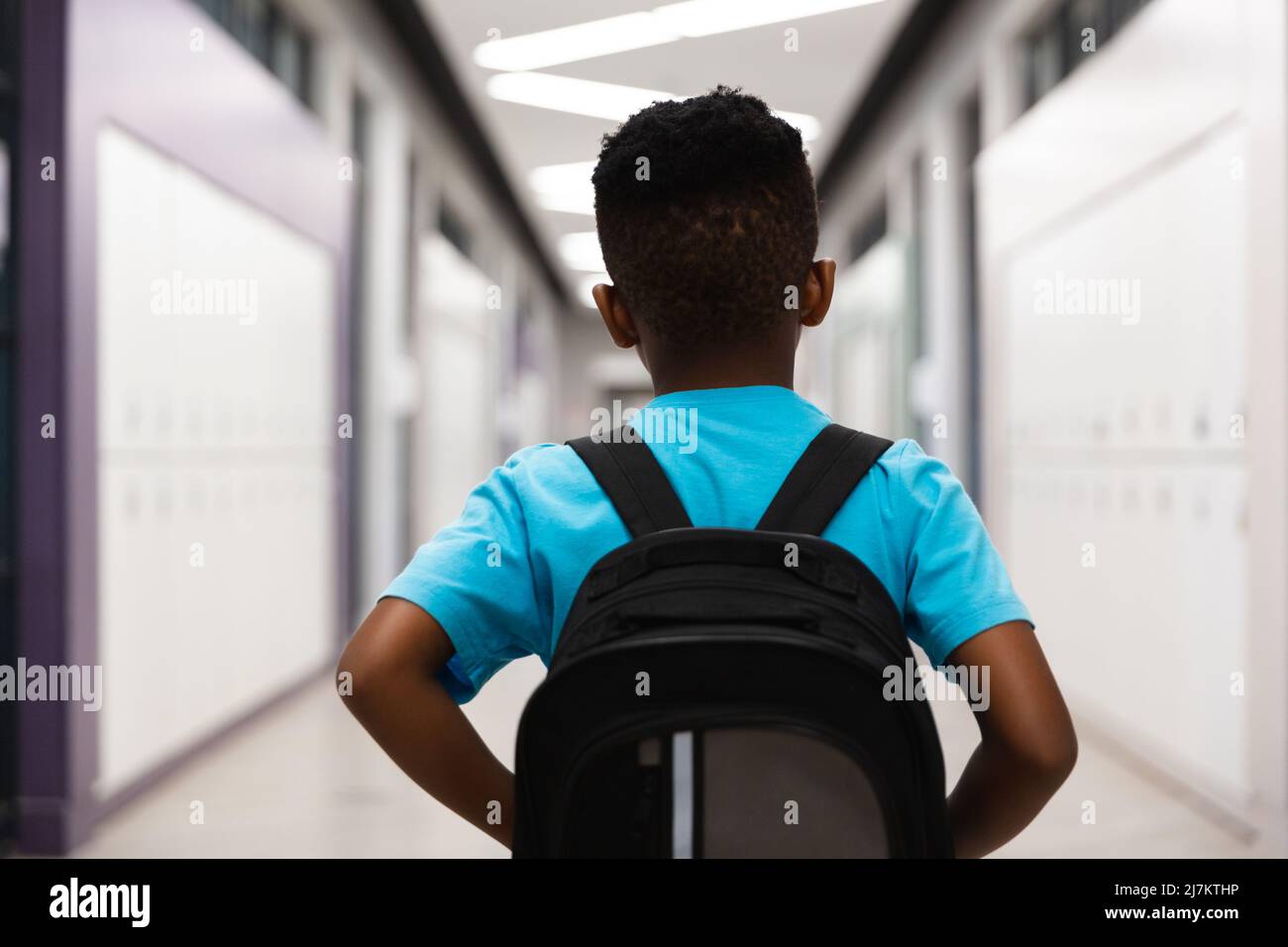 Rear view of african american elementary schoolboy with backpack ...