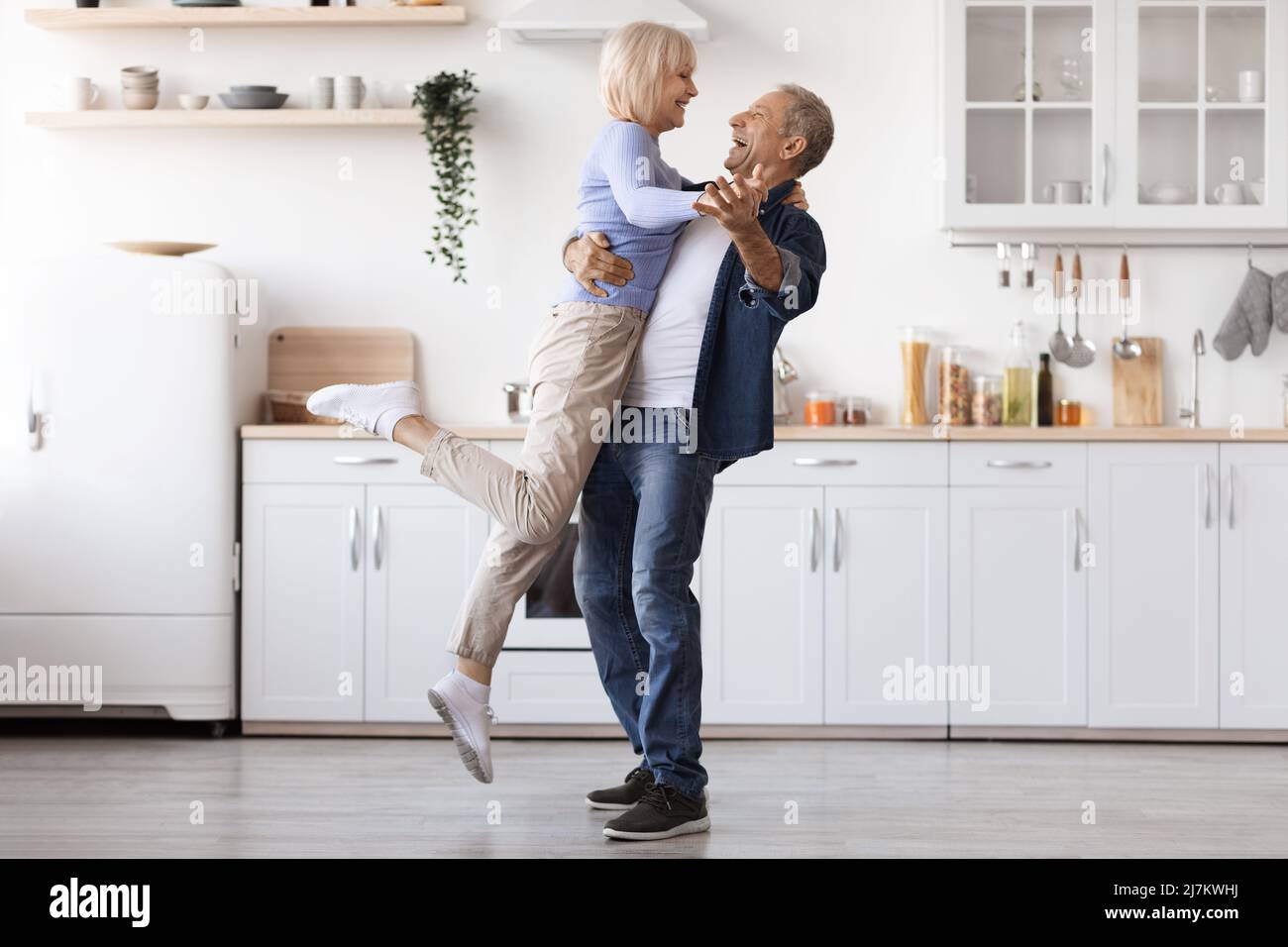 Romantic elderly man and woman dancing at kitchen Stock Photo