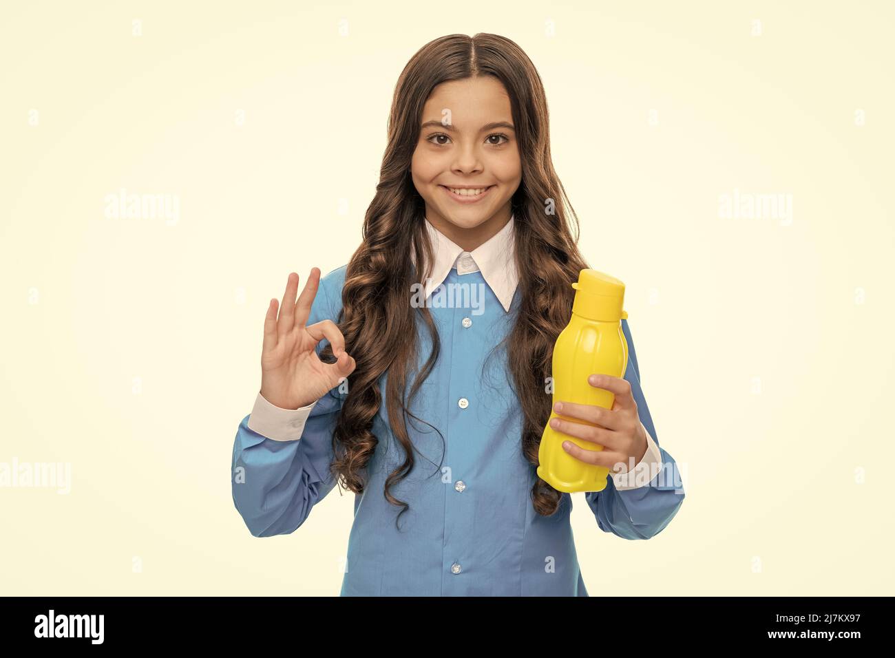 Happy girl show OK sign holding yellow plastic drinking water bottle