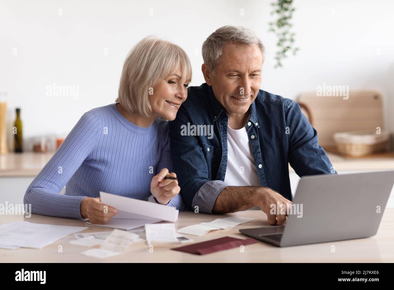 Happy senior couple paying bills online, using computer Stock Photo