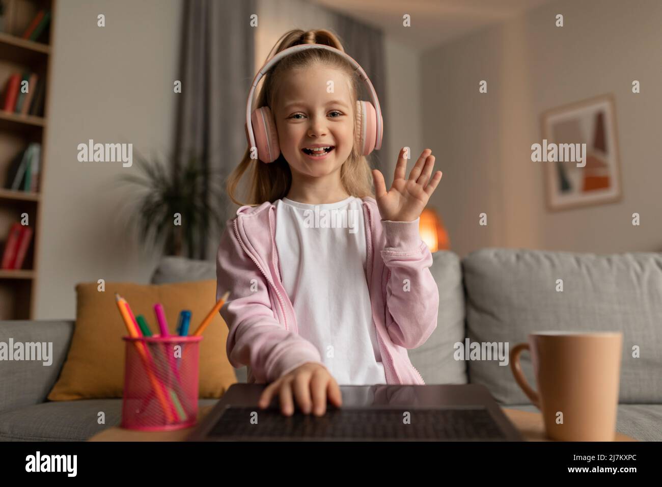 Little Girl Waving Hand To Laptop Video Calling At Home Stock Photo - Alamy