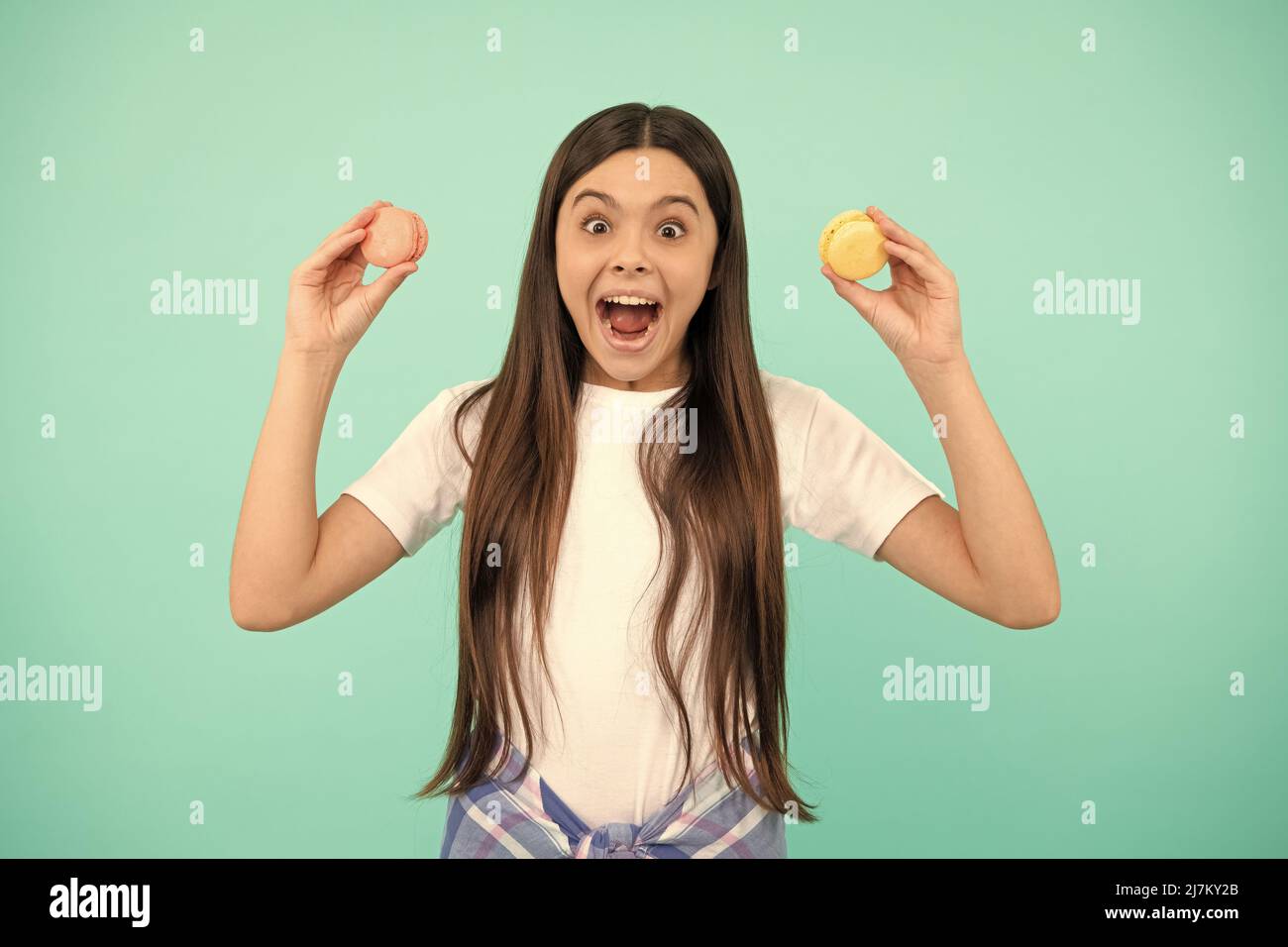 amazed teen girl hold french macaron or macaroon cookies, childhood Stock Photo
