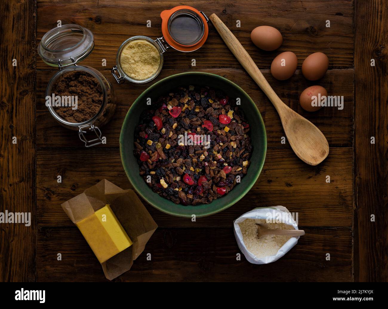 Flat lay on a dark wooden table of ingredients ready to make a fruit cake. Stock Photo