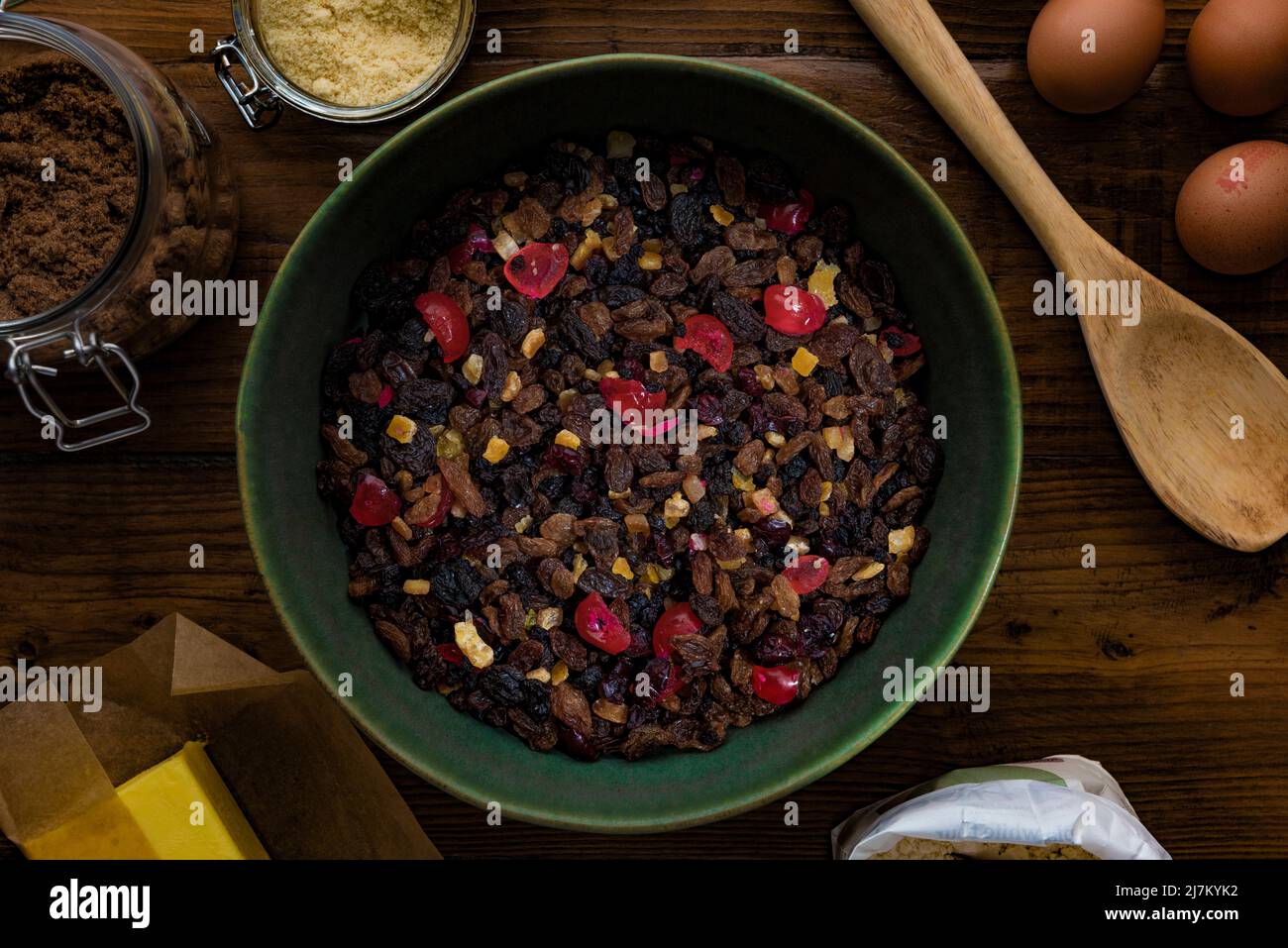 Flat lay composition on a dark wooden table of ingredients ready to make a fruit cake. Stock Photo