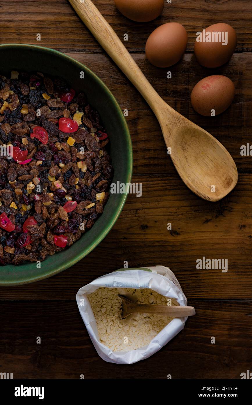 Flat lay composition on a dark wooden table of ingredients ready to make a fruit cake. Stock Photo