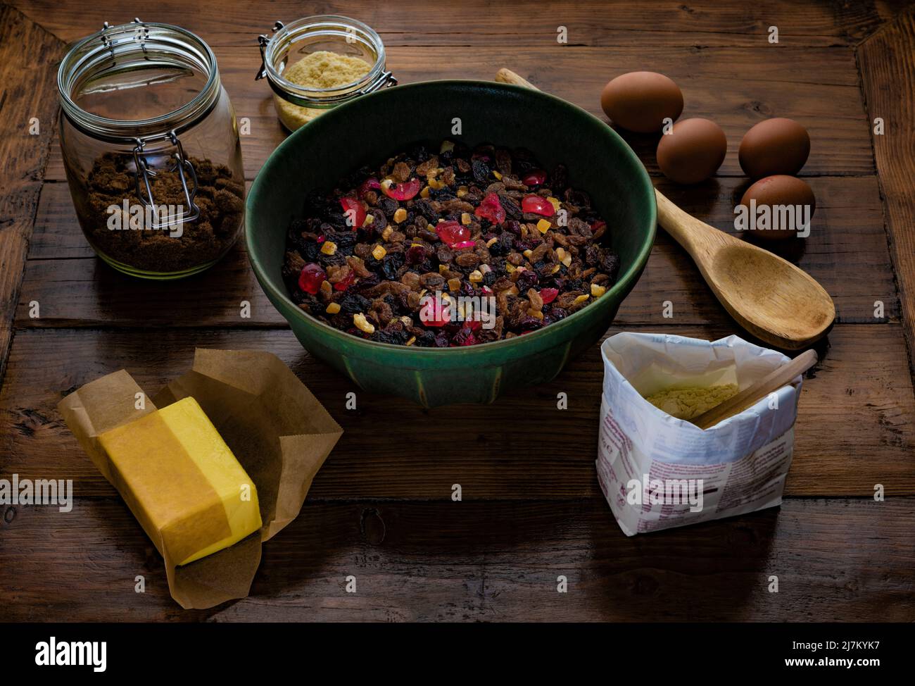 Ingredients assembled ready to make a fruit cake on a dark wooden table. Stock Photo