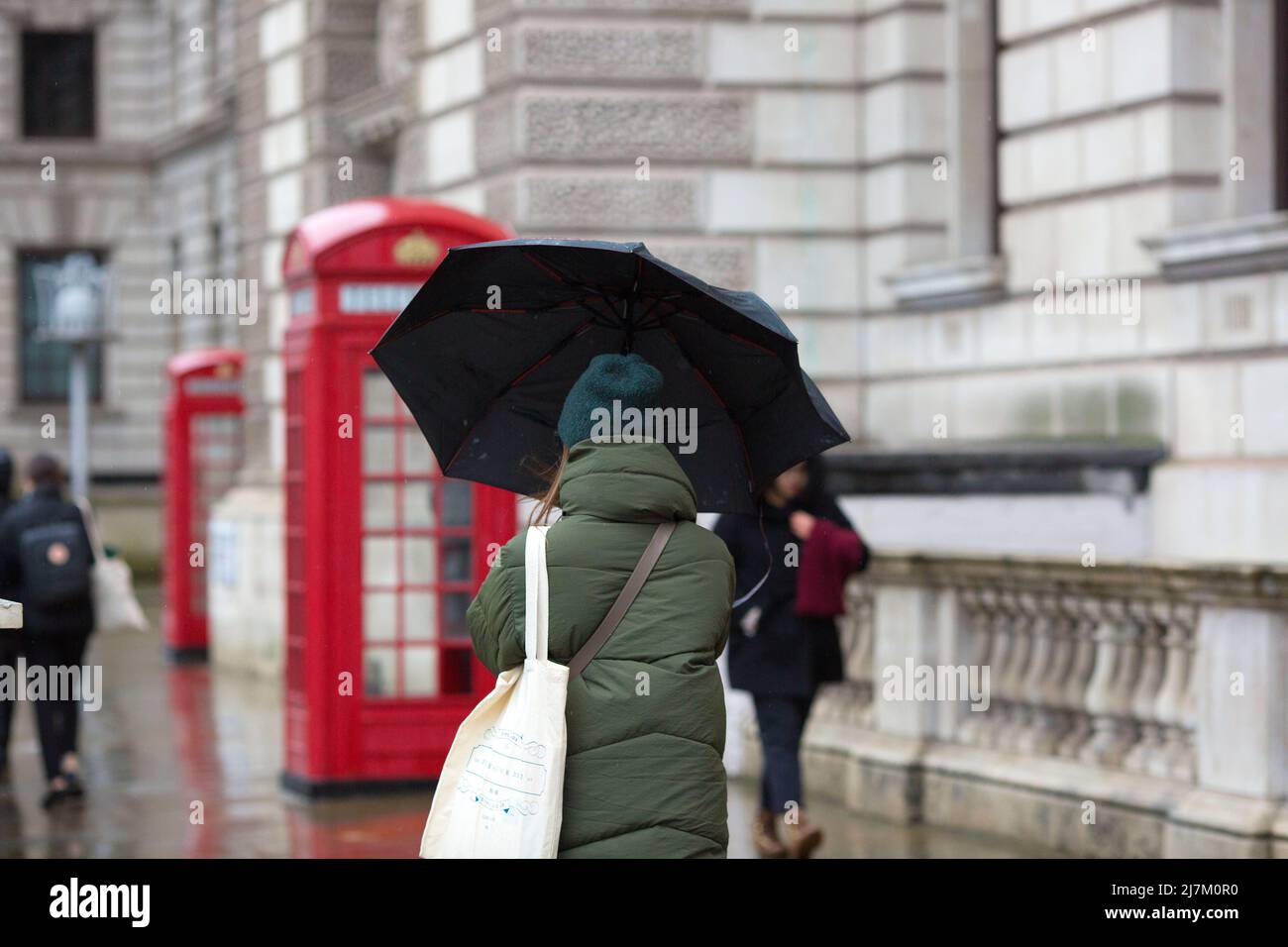 The umbrellas held by a pedestrian is seen blown by the wind in Westminster, central London. Stock Photo
