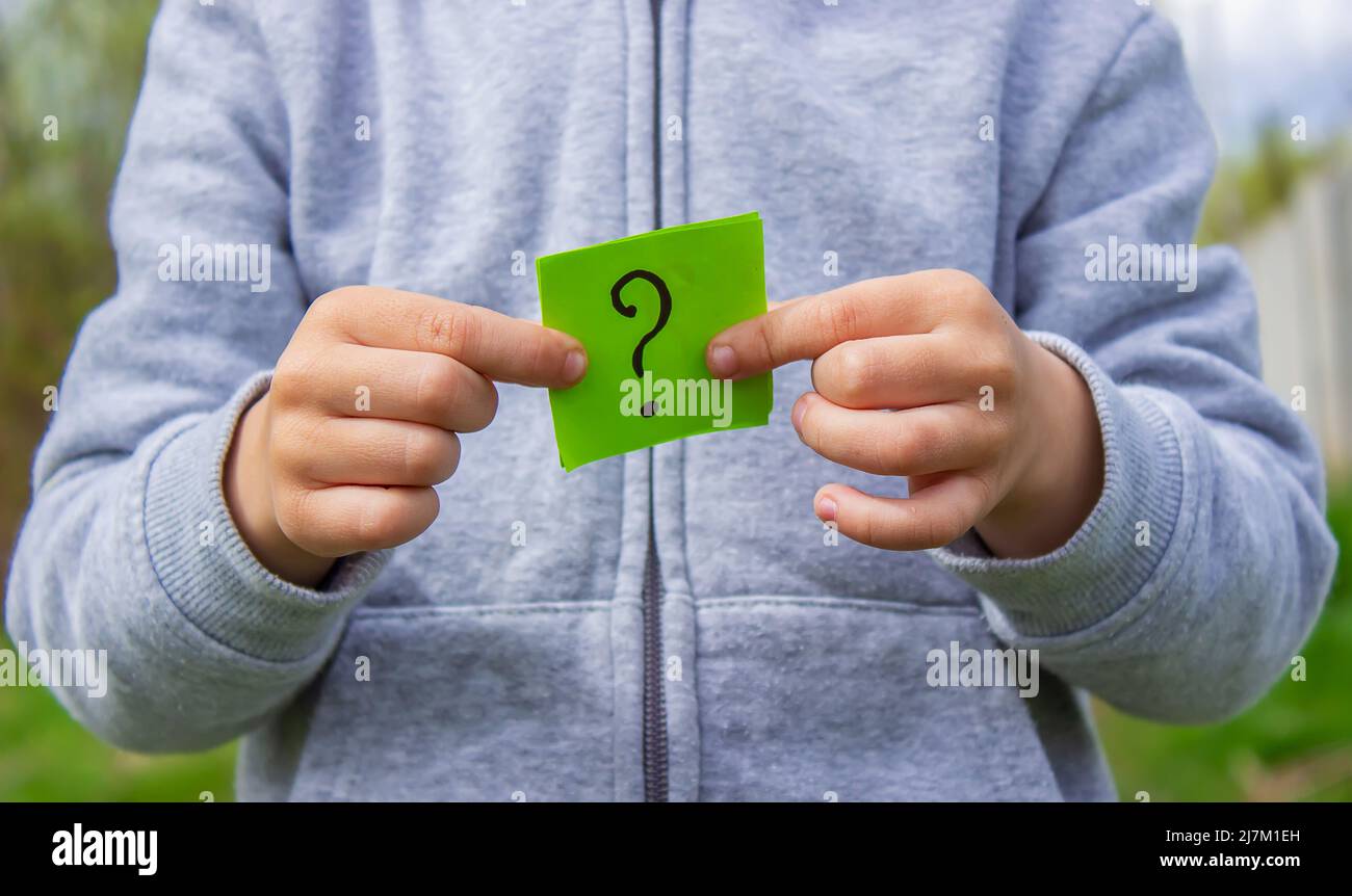 the boy holds stickers with a question mark on the background of the ...
