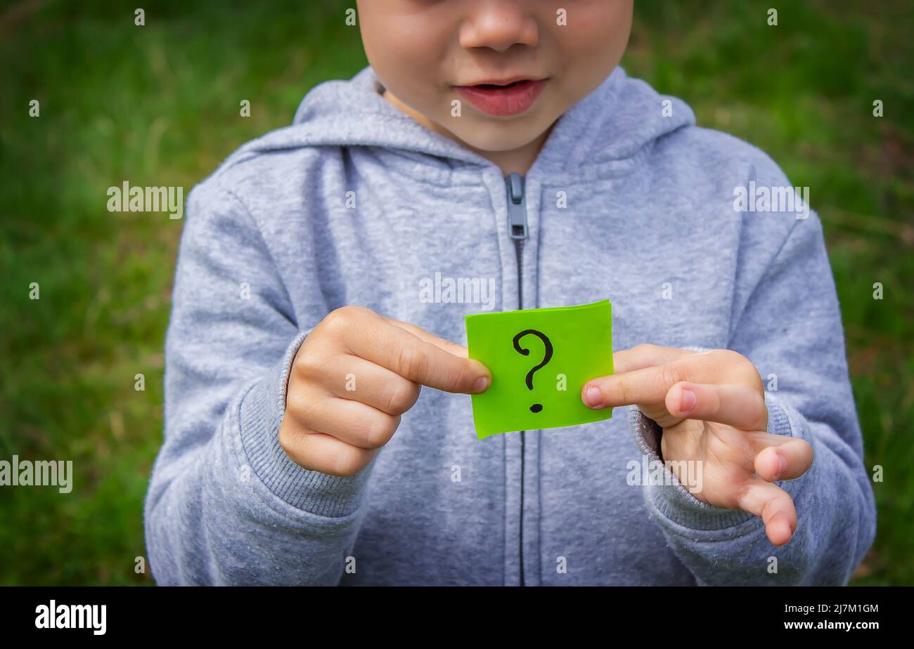 the boy holds stickers with a question mark on the background of the ...
