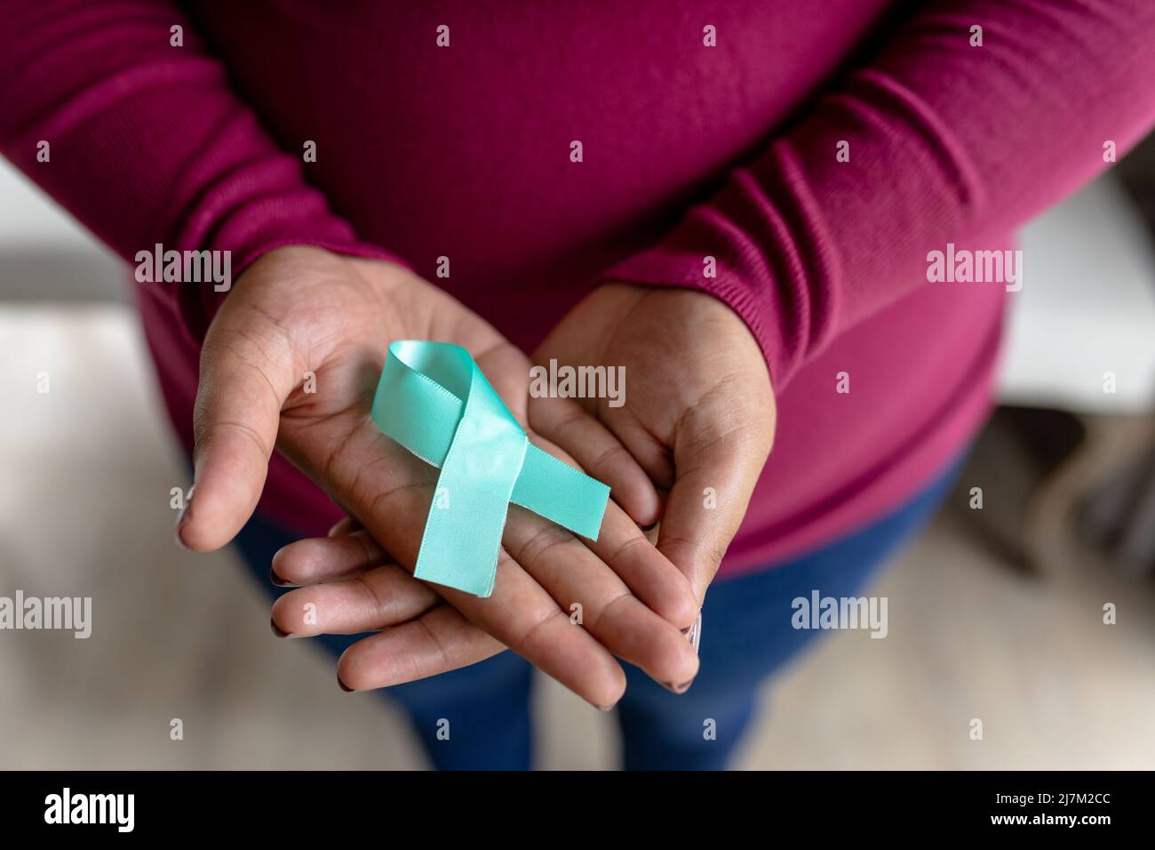 Midsection of african american mid adult woman with prostate cancer awareness blue ribbon Stock Photo