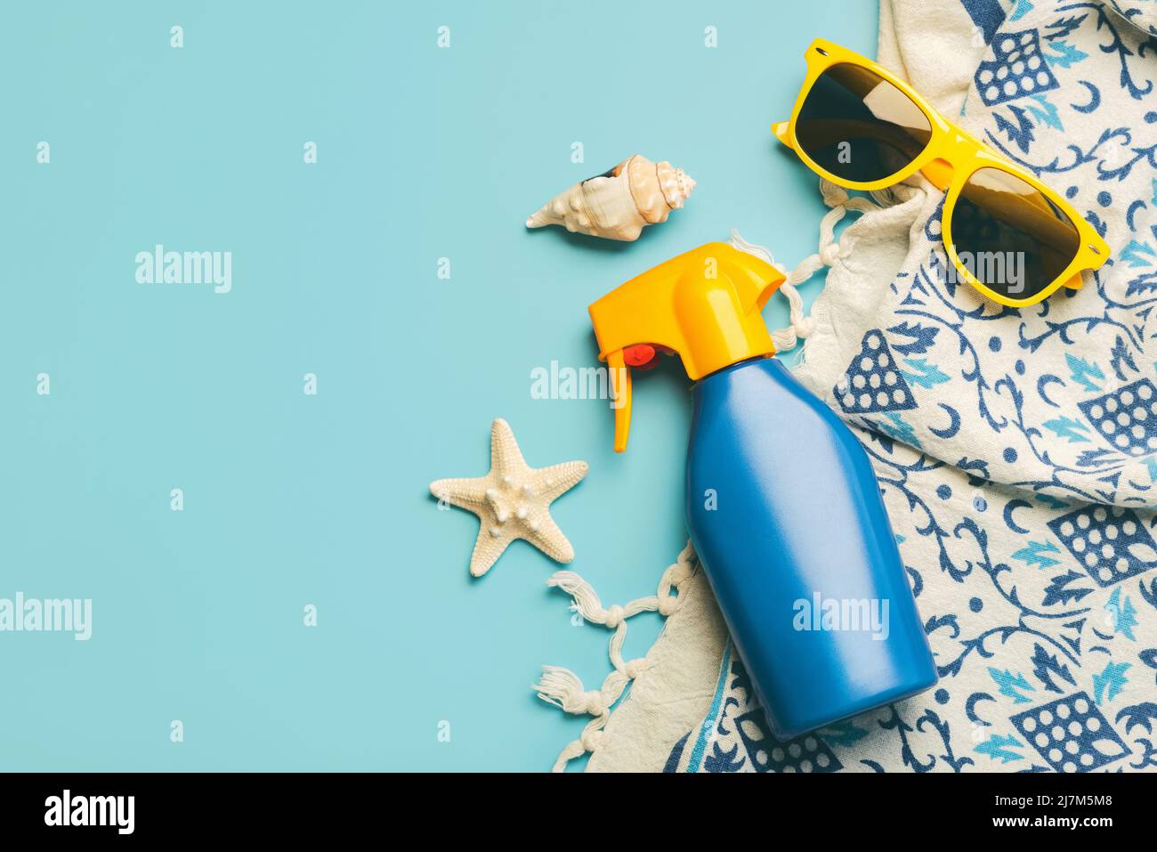 Summer holiday concept.Top view of beach towel,sunglasses and sunscreen with space for text over blue background Stock Photo