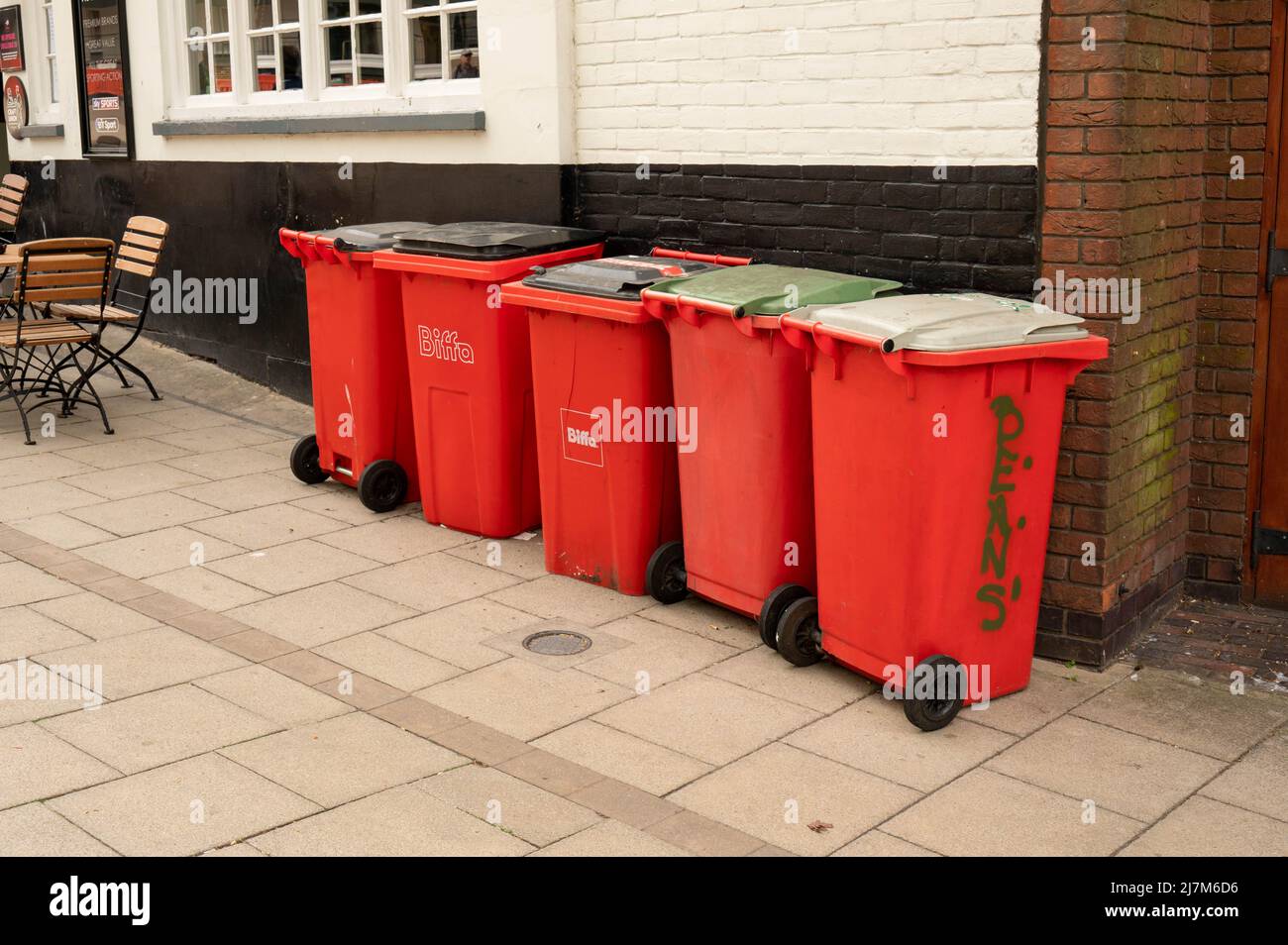A row of red wheelie bins on the pavement in a street in Norwich city