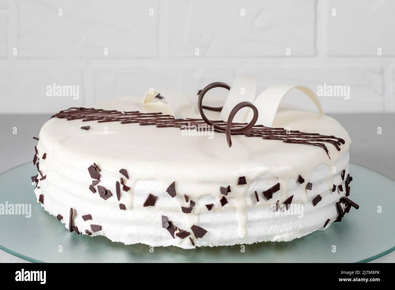 White cake decorated with chocolate decor on a glass plate on a gray background. Selective focus. Stock Photo