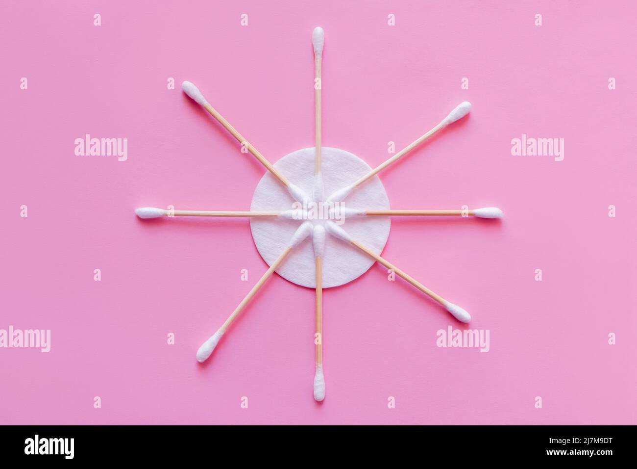 flat lay of cosmetic ear sticks near white cotton pad on pink background, top view Stock Photo