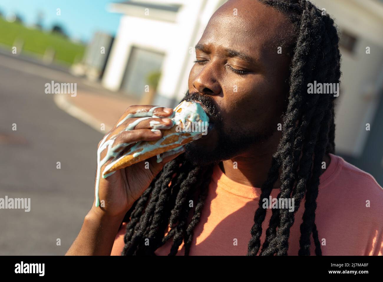 African american man eating melting ice cream with messy hand on sunny day Stock Photo