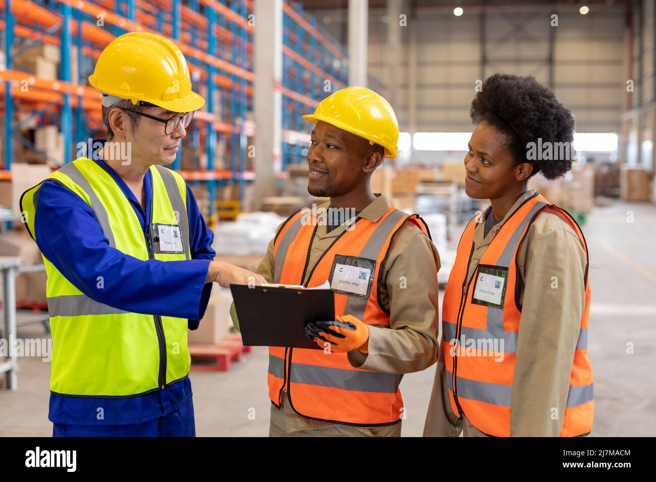 Asian mature foreman explaining over clipboard to african american young male and female workers Stock Photo