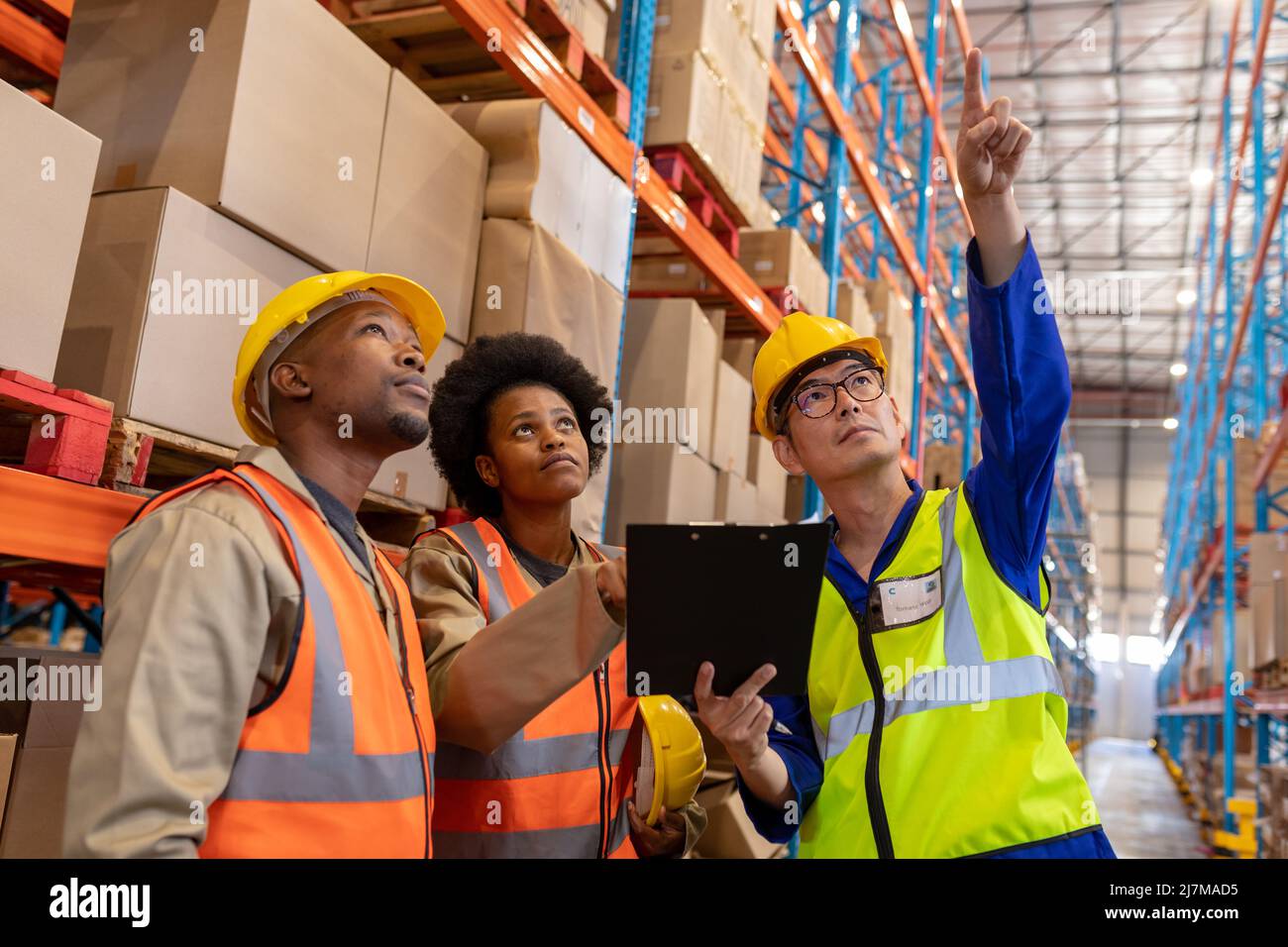 Asian mature foreman pointing upwards and african american young male and female workers looking up Stock Photo