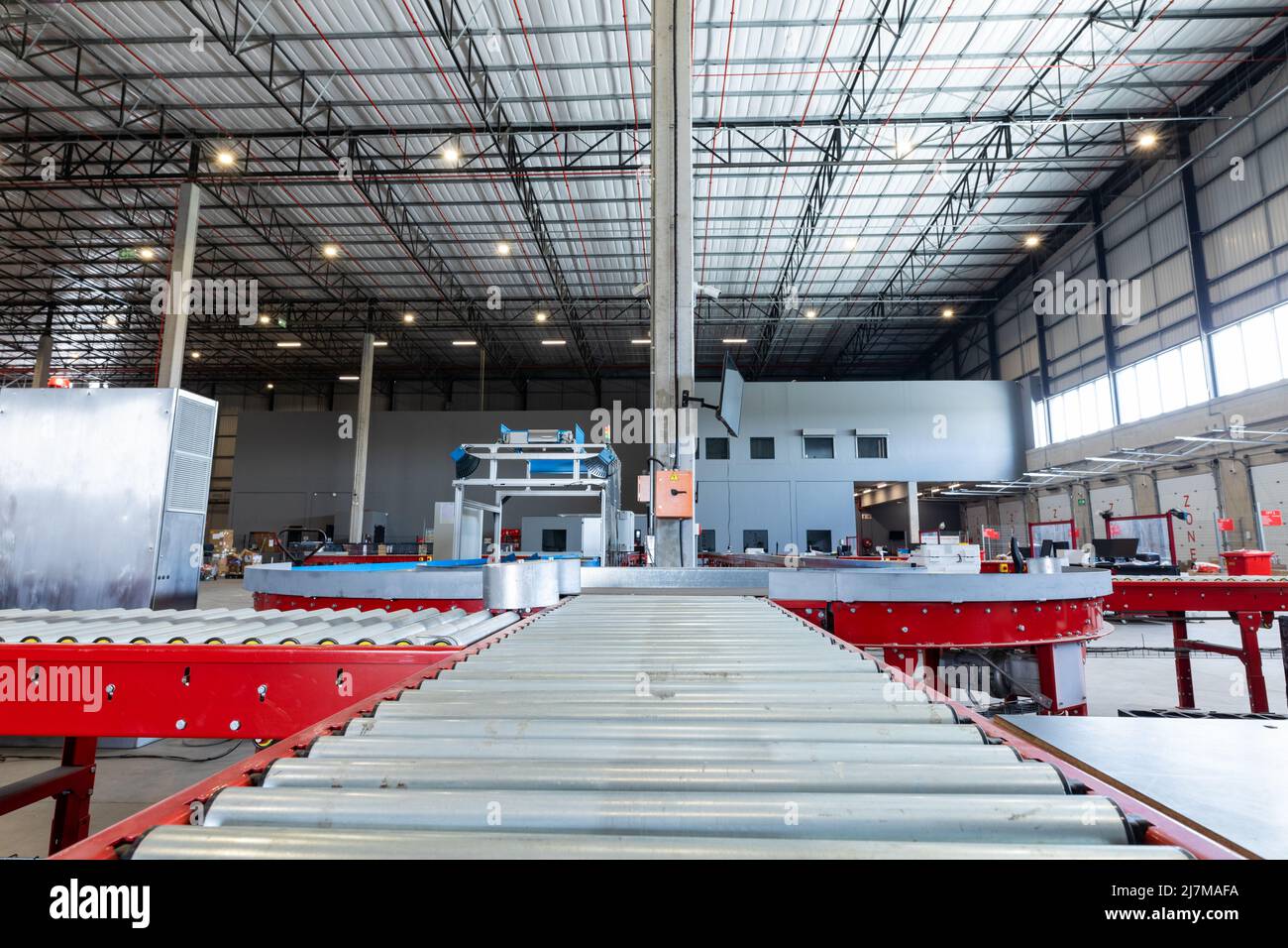 Empty conveyor belt with illuminated lights hanging on ceiling in distribution warehouse Stock Photo