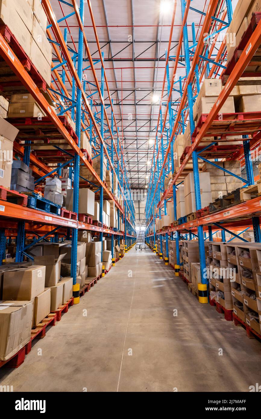 Diminishing perspective of flooring amidst shelves with cardboard boxes in distribution warehouse Stock Photo