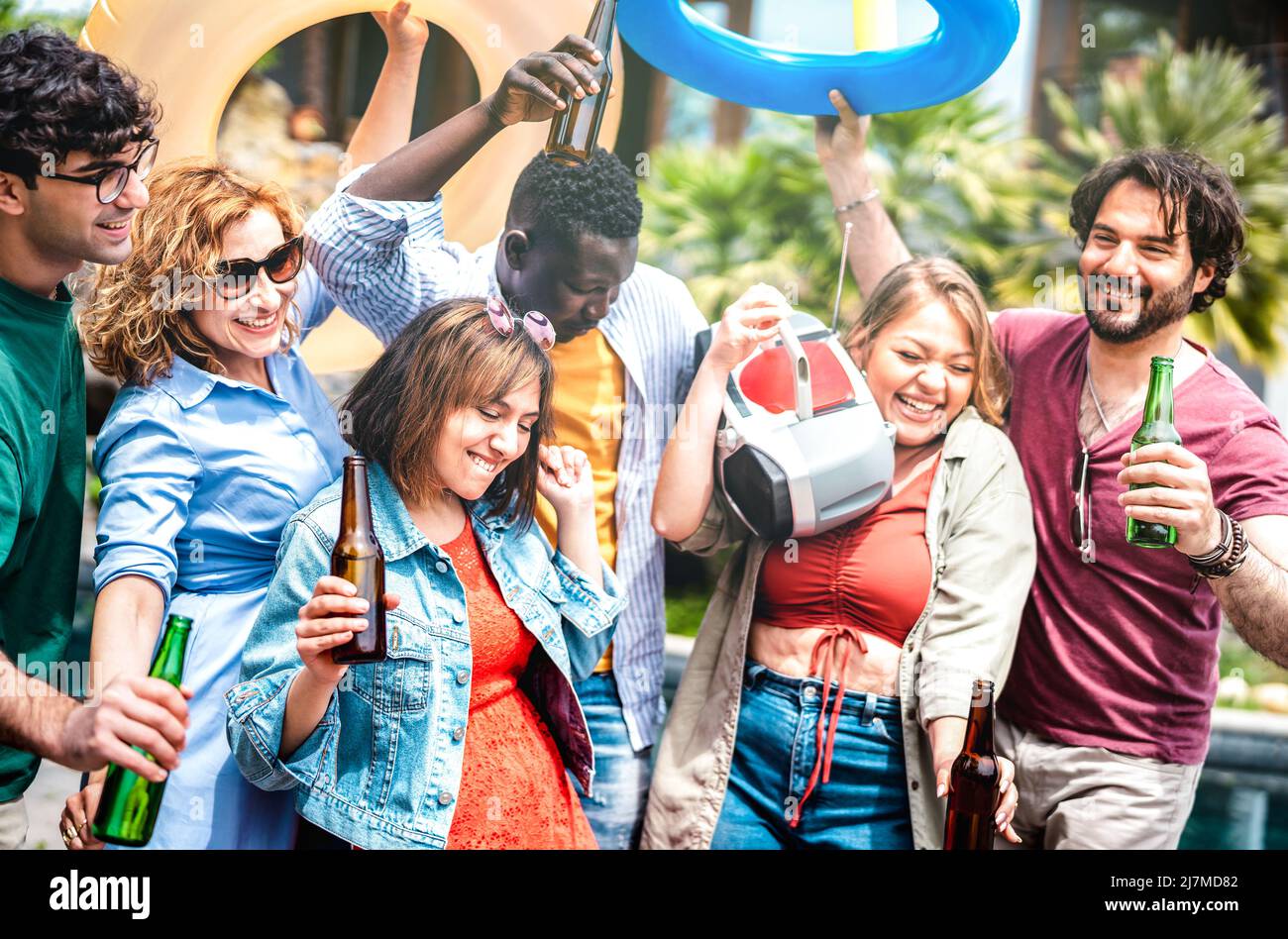 Multicultural friends group having fun out side cheering with boombox and beer bottles - Gen z people enjoying spring break party festival together - Stock Photo