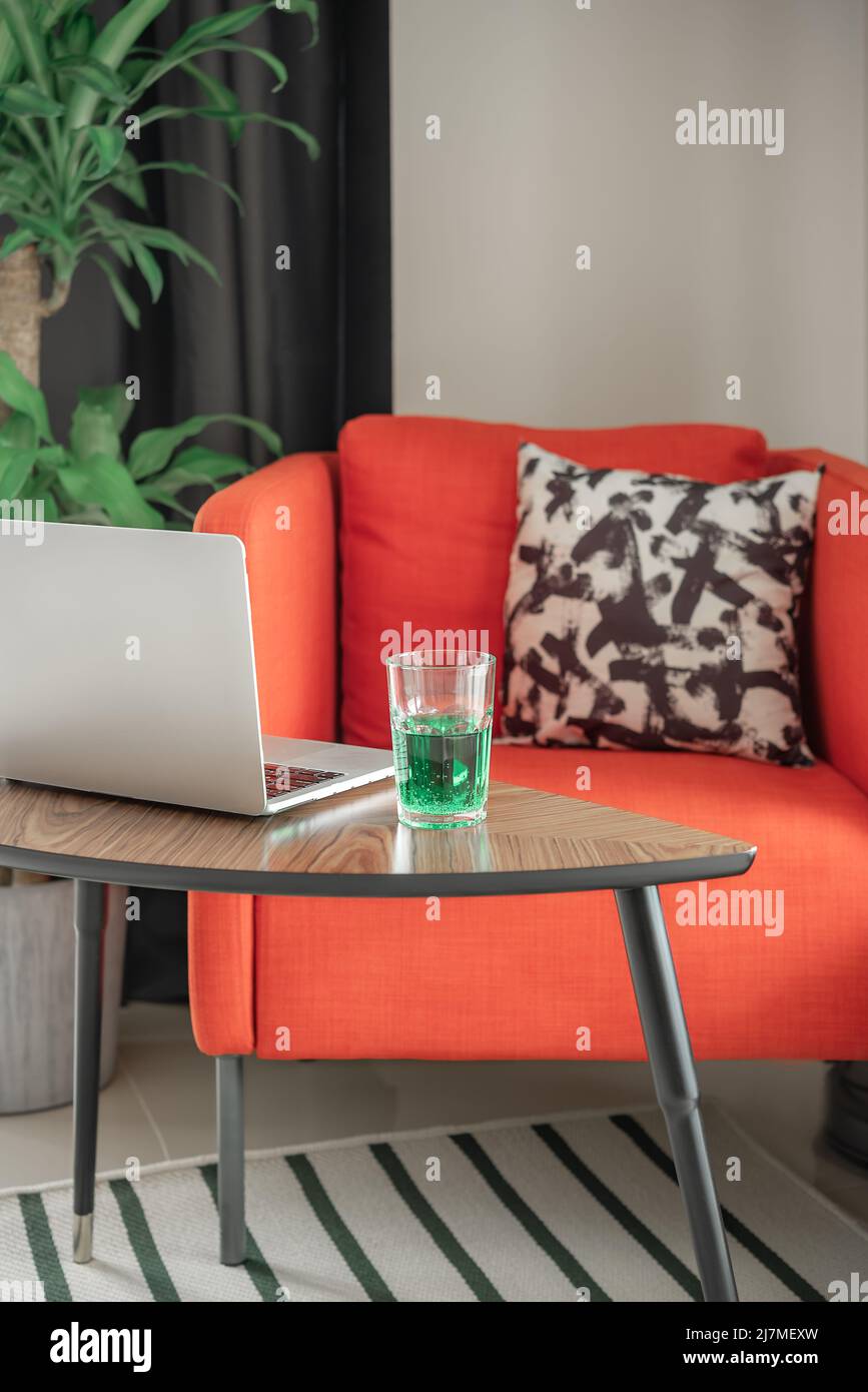 Cozy armchair, laptop and a glass of drink. Vertical shot. Stock Photo