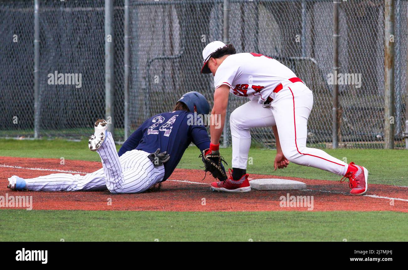 A baseball player is diving back to first base during a pick off play  during a high school baseball game Stock Photo - Alamy