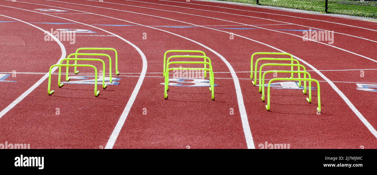 Three rows of yellow mini hurdles set up in lanes on a track for