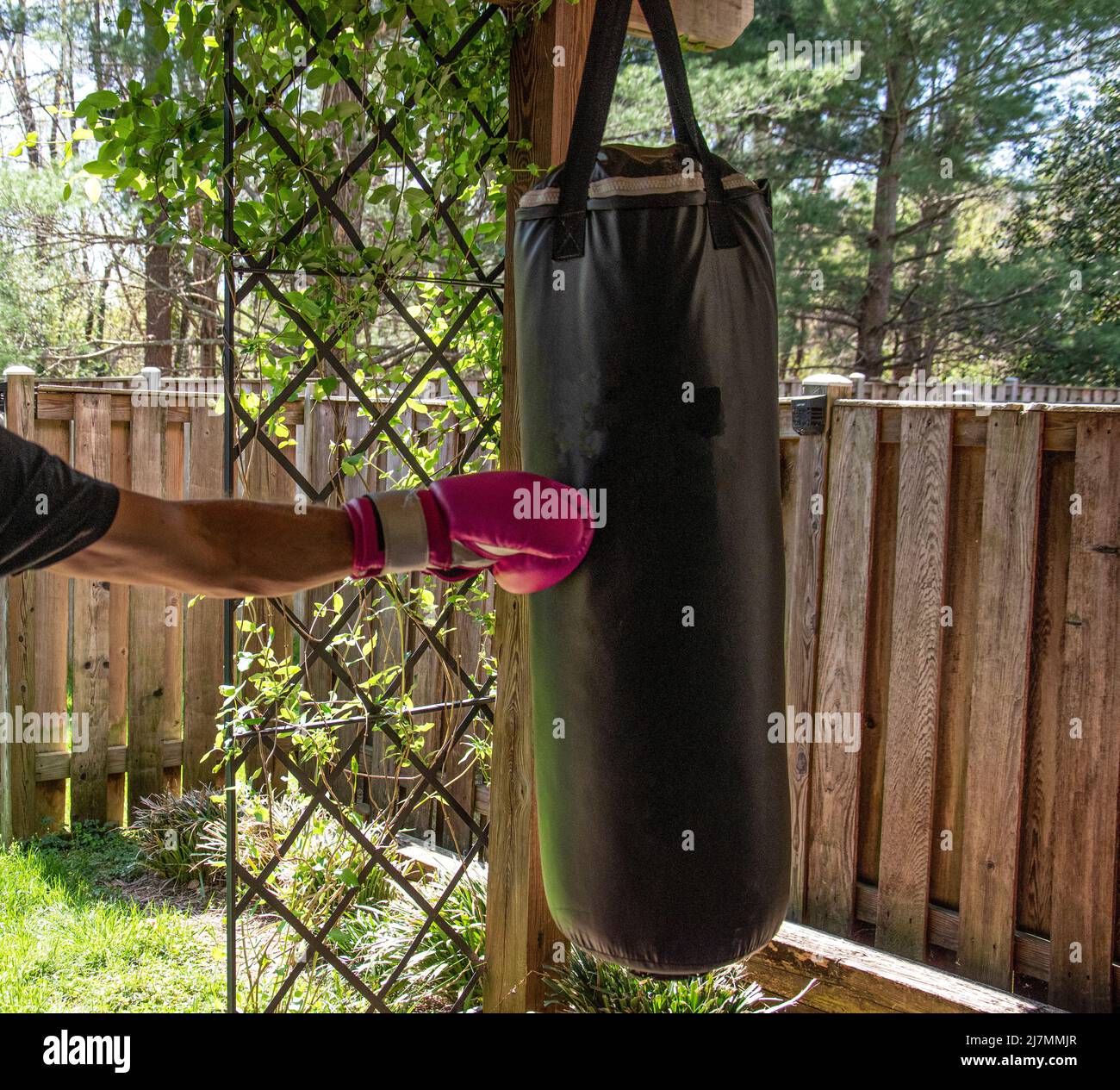 A man exercising in an outdoor home gym, using bright pink boxing