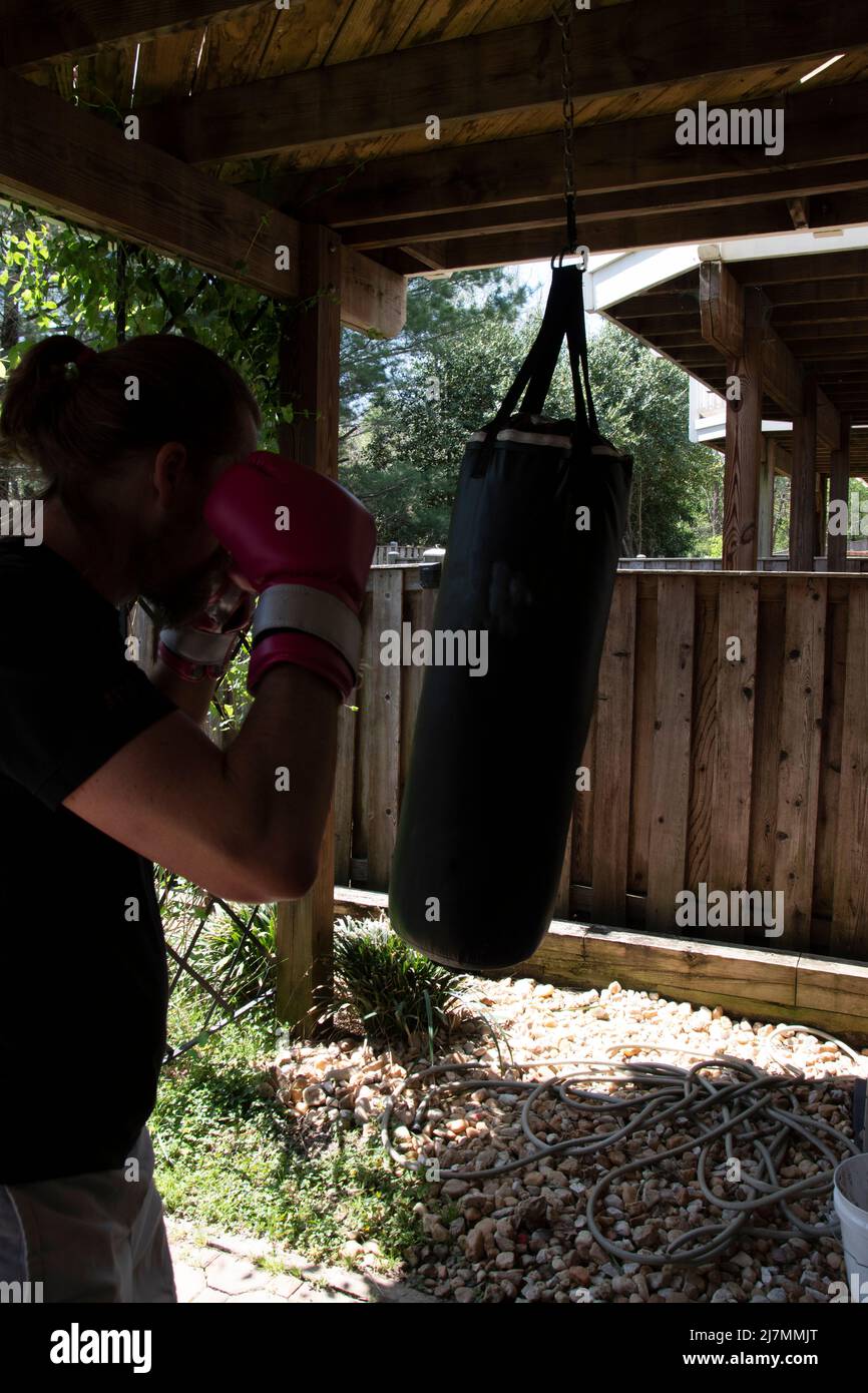 A man exercising in an outdoor home gym, using bright pink boxing