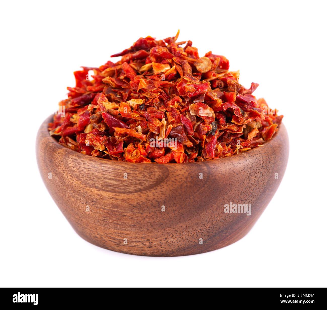 Dried red paprika flakes in wooden bowl, isolated on white background