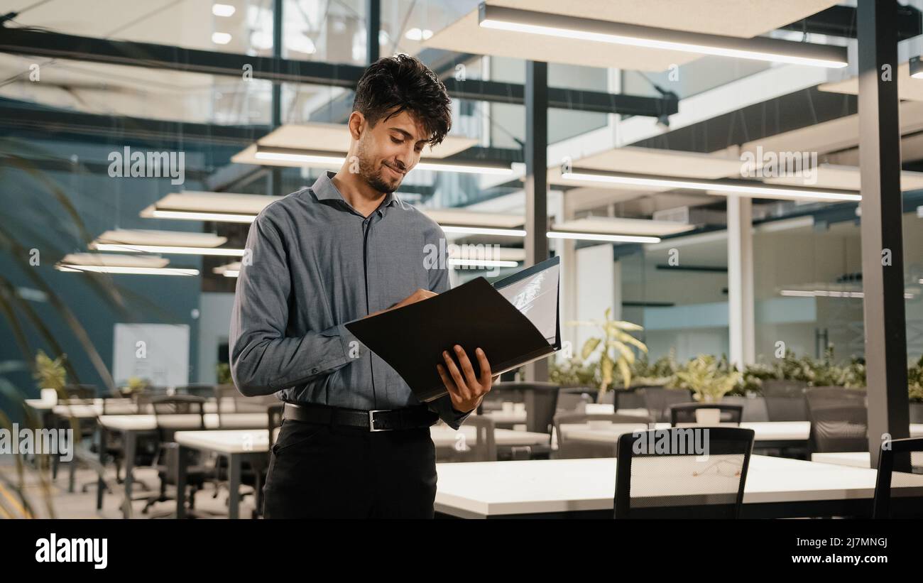 Young arabian confident business man guy stand in modern office hold
