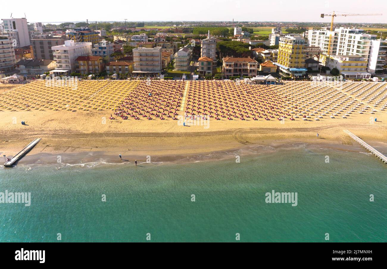 Spiaggia dorata di Jesolo - Baia e ombrelloni in una lunga vista del mare dall'alto durante la giornata di sole con il palazzo della città della città Stock Photo