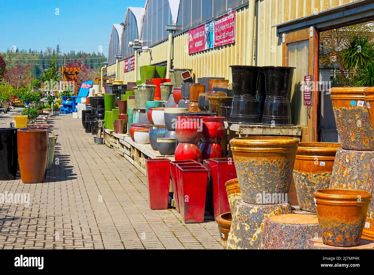 A variety of colourful ceramic plant pots on display stacked outside a garden centre. Stock Photo