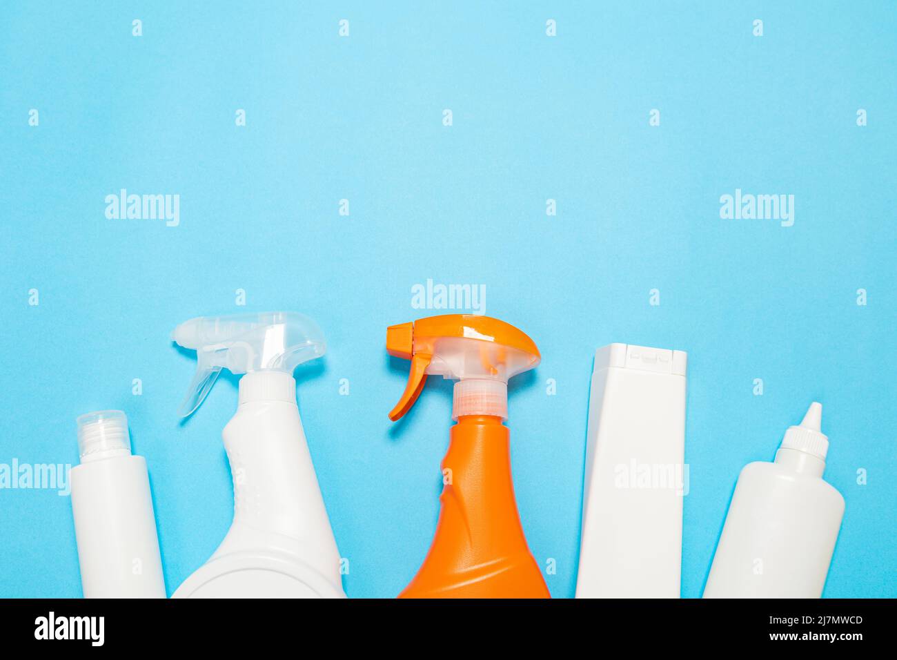 House cleaning supplies on blue background. Row of plastic bottles with