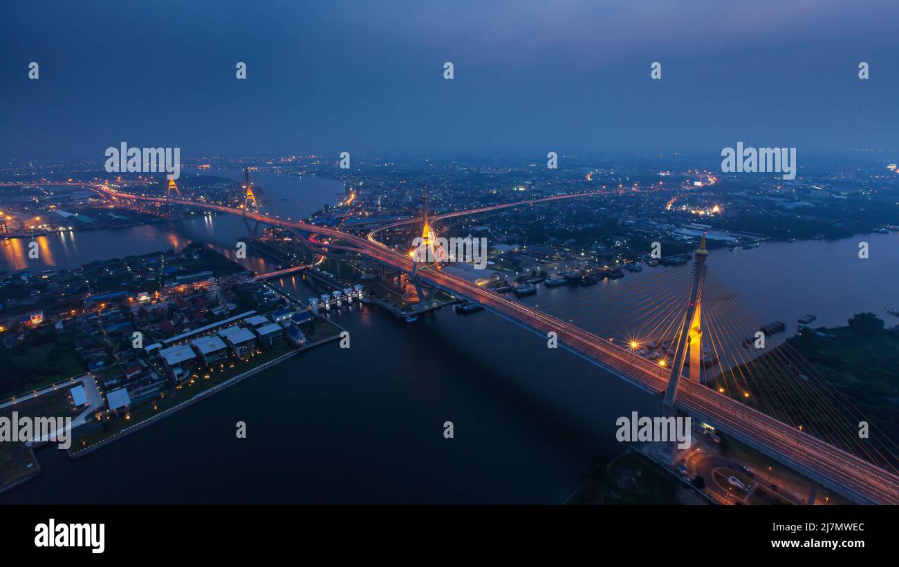 High angle view of the suspension bridges and highway interchange over Chao Phraya River at dusk, illuminated lights trails on the bridge. Thailand. Stock Photo