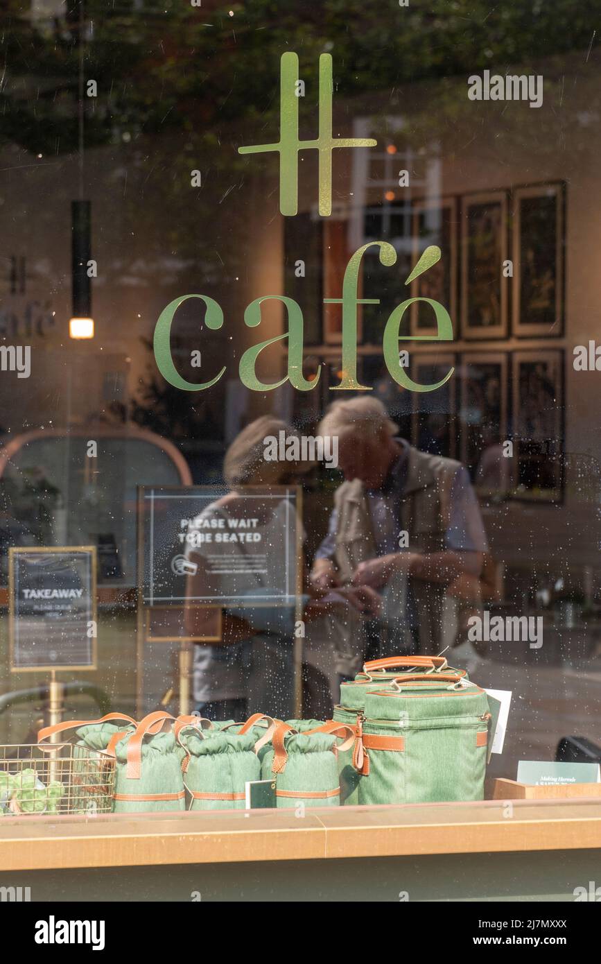 Mature couple reflected in the window of the H Cafe (Harrods), Henley-on-Thames, Oxfordshire, UK Stock Photo