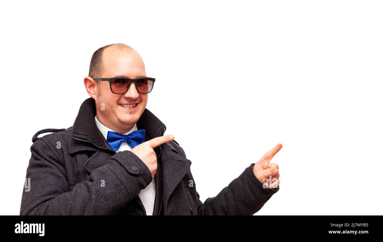 Smiling bald adult Caucasian male wearing a suit, white shirt, blue bow tie and dark jacket, isolated on a white background pointing his index fingers Stock Photo